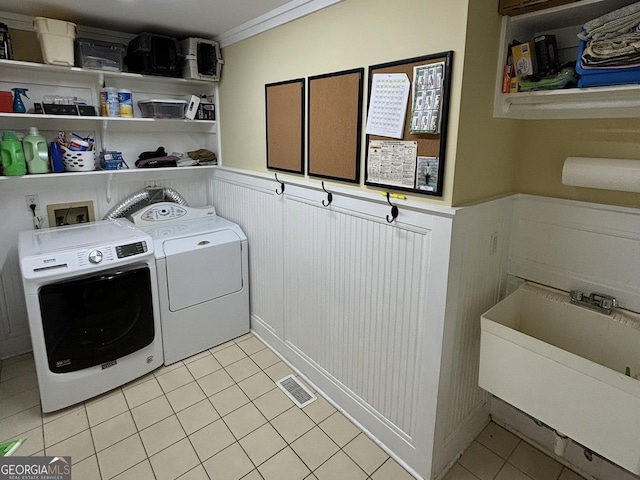 clothes washing area featuring laundry area, light tile patterned floors, visible vents, washer and clothes dryer, and a wainscoted wall