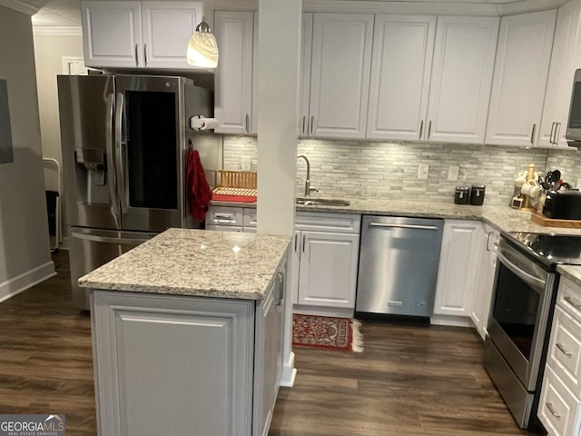 kitchen featuring a center island, stainless steel appliances, decorative backsplash, white cabinetry, and a sink