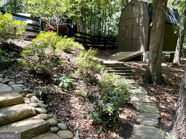 view of yard featuring an outbuilding, a shed, and fence