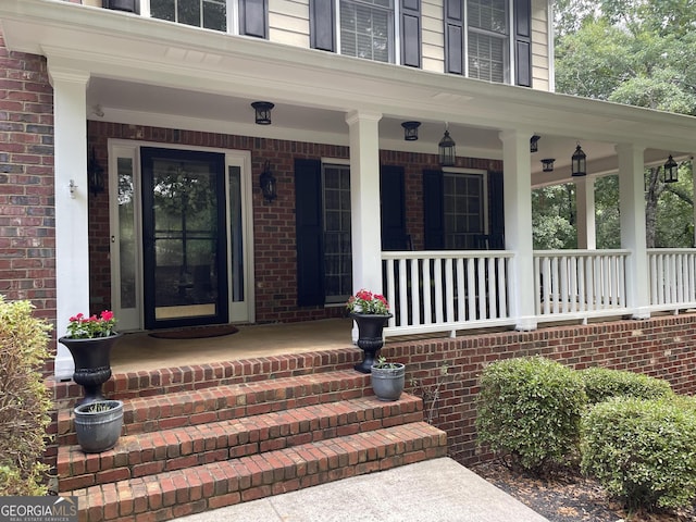 entrance to property featuring covered porch and brick siding