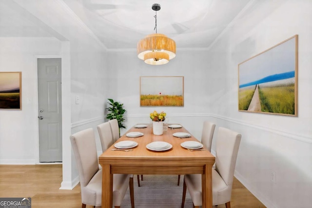 dining area featuring baseboards, ornamental molding, and light wood-style floors