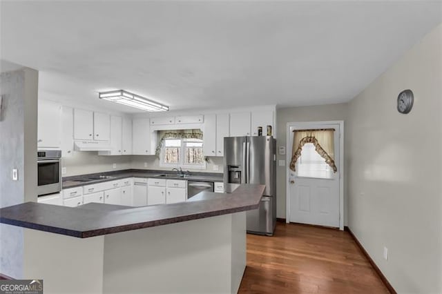 kitchen featuring appliances with stainless steel finishes, dark countertops, white cabinets, and under cabinet range hood