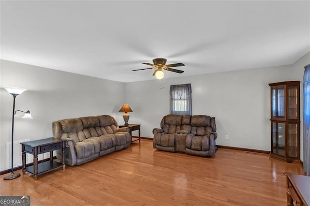 living area with wood finished floors, a ceiling fan, and baseboards