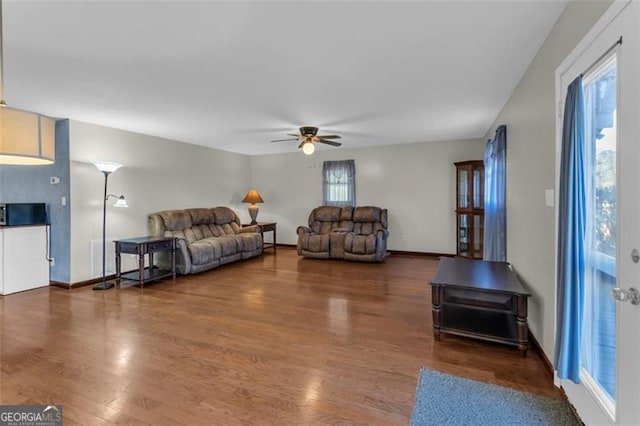 living room with ceiling fan, wood finished floors, and baseboards