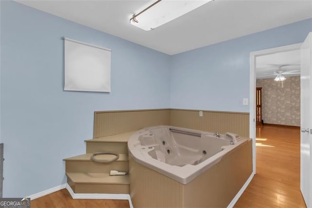 bathroom featuring wainscoting, a jetted tub, and wood finished floors