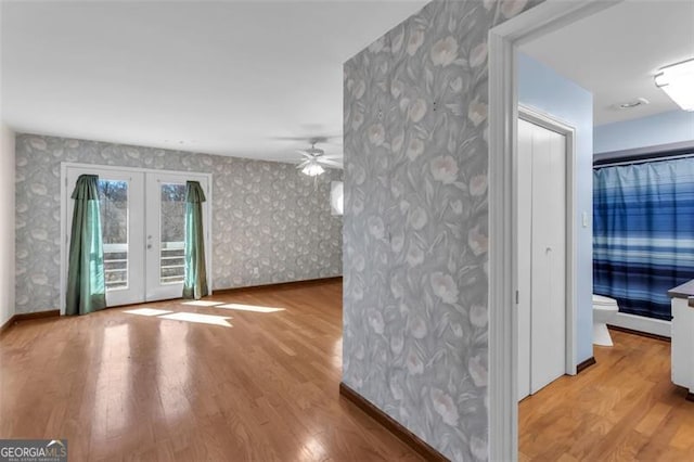 interior space featuring wood finished floors, baseboards, french doors, and wallpapered walls