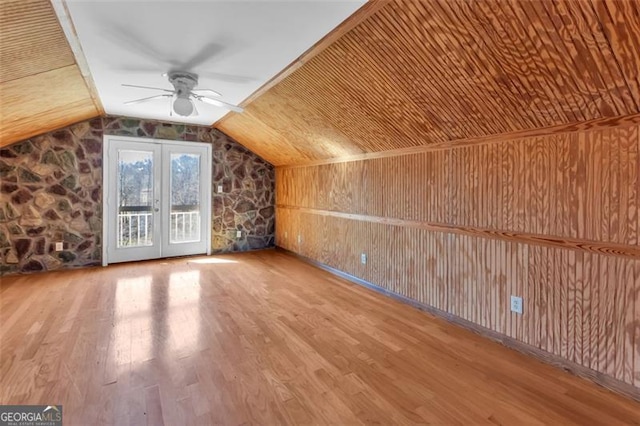 bonus room with ceiling fan, wooden walls, vaulted ceiling, and wood finished floors