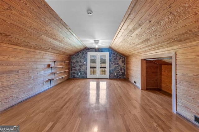 additional living space with visible vents, lofted ceiling, wood ceiling, wood finished floors, and wood walls