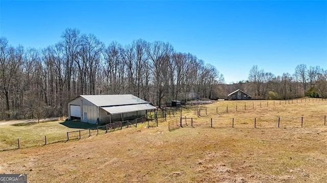 view of yard featuring a garage, a rural view, an outbuilding, a pole building, and fence