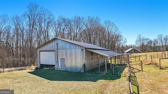 view of pole building with driveway, a lawn, and fence