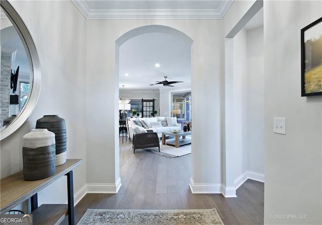 corridor featuring baseboards, arched walkways, dark wood finished floors, crown molding, and recessed lighting