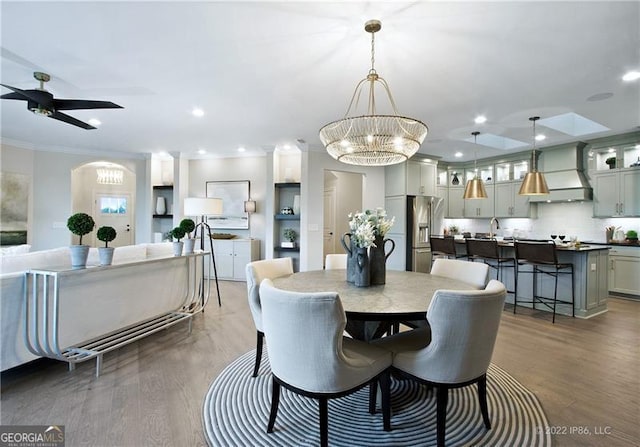 dining area with ceiling fan with notable chandelier, ornamental molding, wood finished floors, and recessed lighting