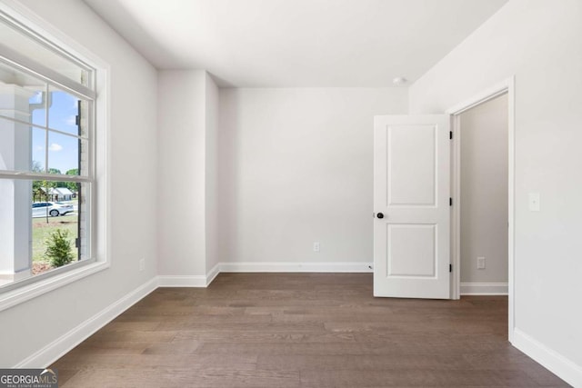 unfurnished room featuring wood finished floors, a wealth of natural light, and baseboards