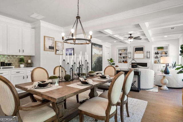 dining space with beam ceiling, light wood-style floors, ornamental molding, a ceiling fan, and coffered ceiling