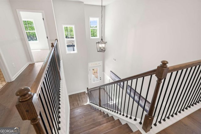 staircase featuring a notable chandelier, baseboards, and wood finished floors