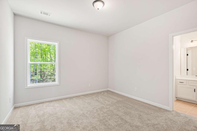 empty room with baseboards, visible vents, and light colored carpet