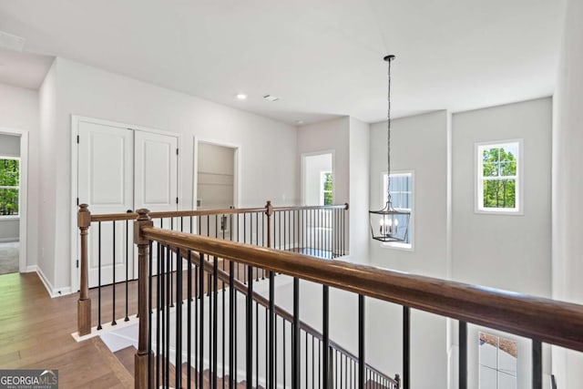 hall with dark wood-style flooring, a notable chandelier, recessed lighting, an upstairs landing, and baseboards