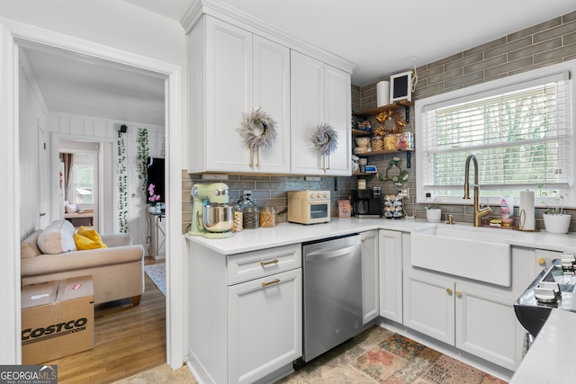 kitchen featuring light countertops, decorative backsplash, white cabinetry, a sink, and dishwasher