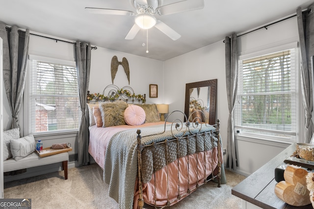 bedroom with multiple windows, ceiling fan, and light carpet