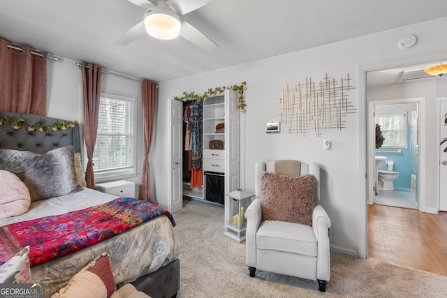 bedroom featuring light carpet, baseboards, connected bathroom, a walk in closet, and a closet