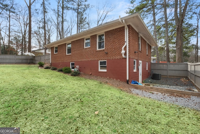 view of home's exterior featuring a fenced backyard, a lawn, central AC, and brick siding