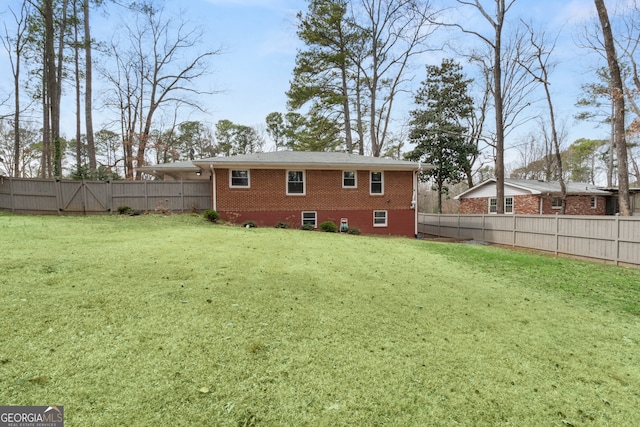 rear view of house featuring a yard, a fenced backyard, a gate, and brick siding