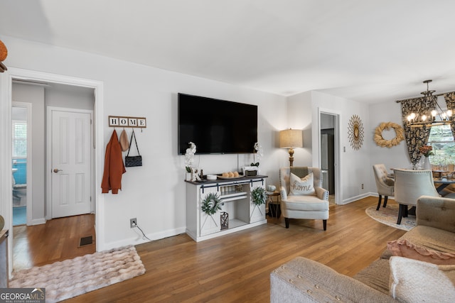 living area featuring baseboards, wood finished floors, visible vents, and an inviting chandelier