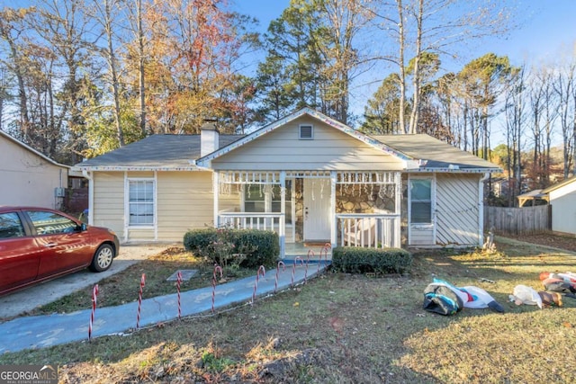 bungalow-style house featuring covered porch, fence, and a chimney