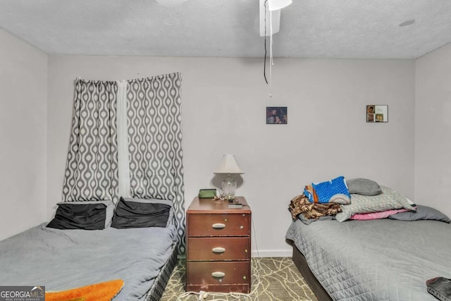 carpeted bedroom with a textured ceiling, ceiling fan, and baseboards