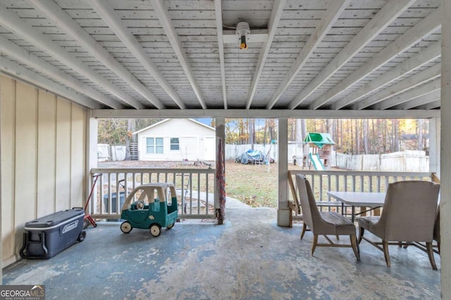 view of patio featuring a fenced backyard, an outbuilding, a storage unit, outdoor dining area, and a playground