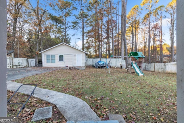 view of yard featuring a playground, an outdoor structure, and a fenced backyard