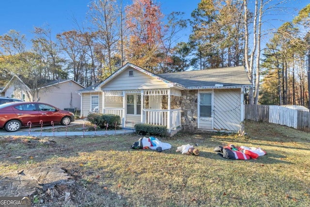 view of front facade featuring stone siding, fence, and a front lawn