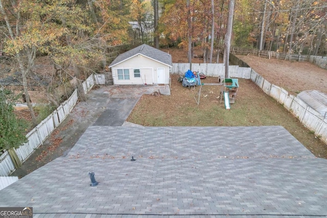 view of front of house with decorative driveway, a fenced backyard, an outdoor structure, and a front lawn