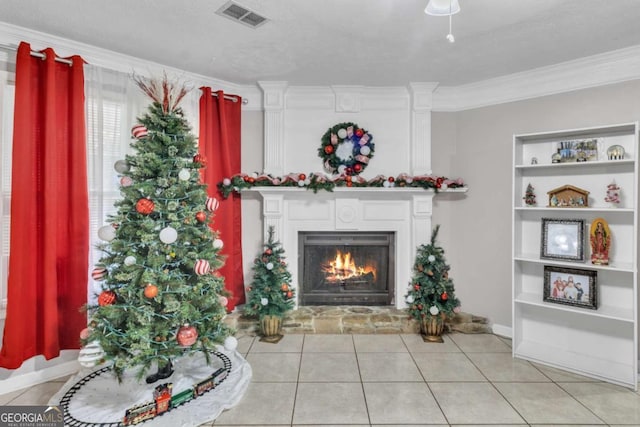 interior space with built in features, visible vents, ornamental molding, a lit fireplace, and baseboards