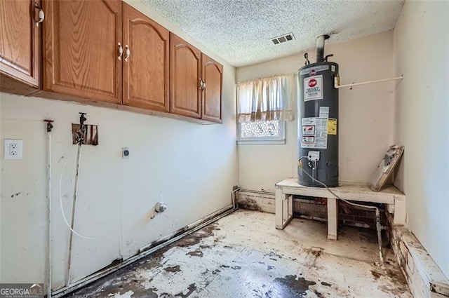 washroom with cabinet space, water heater, visible vents, and a textured ceiling