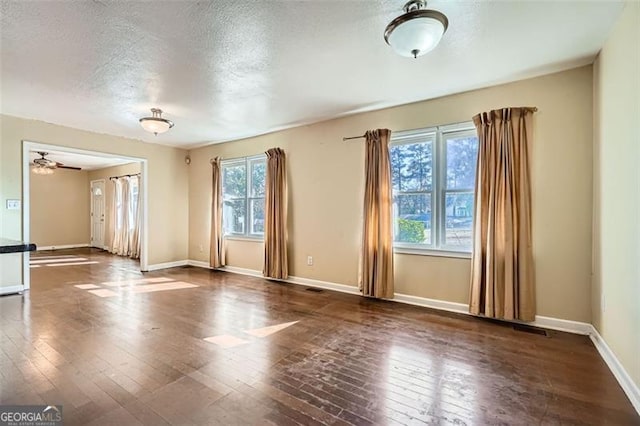 empty room featuring visible vents, baseboards, a textured ceiling, and hardwood / wood-style floors