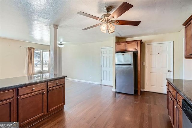 kitchen featuring dark wood-style floors, stainless steel appliances, brown cabinetry, a textured ceiling, and baseboards