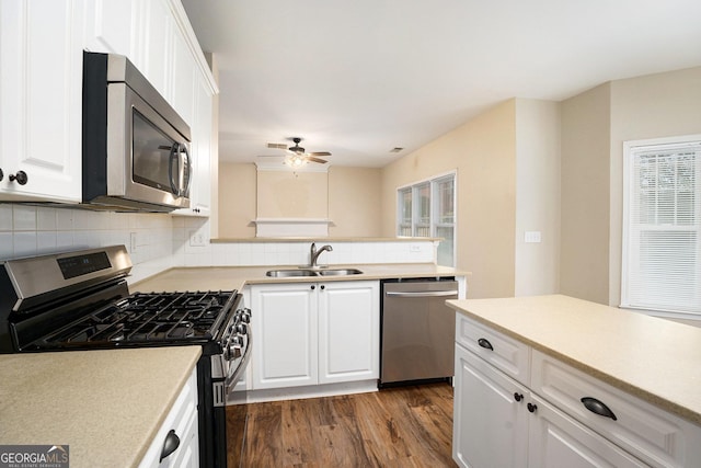 kitchen with dark wood-style flooring, decorative backsplash, appliances with stainless steel finishes, white cabinetry, and a sink