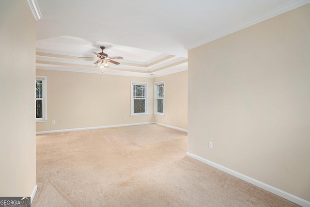 carpeted spare room with baseboards, a tray ceiling, a ceiling fan, and crown molding