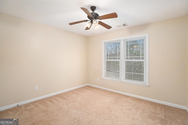 unfurnished room with baseboards, a ceiling fan, visible vents, and light colored carpet