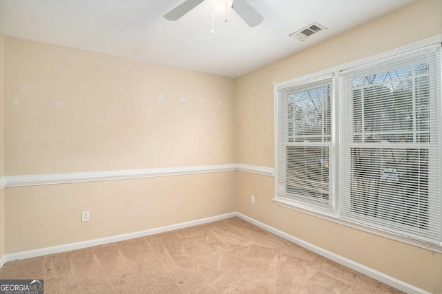 empty room featuring a ceiling fan, light carpet, visible vents, and baseboards