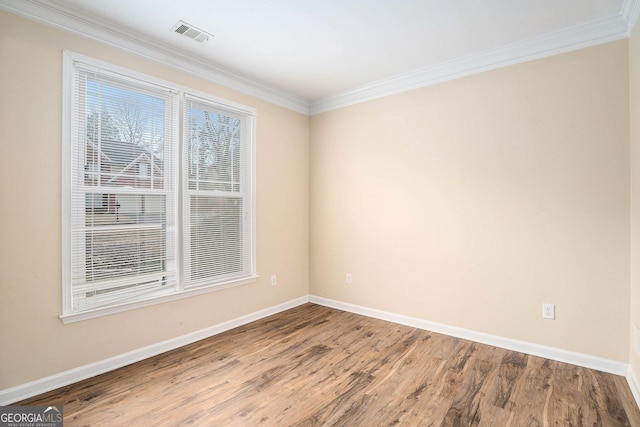 spare room with a wealth of natural light, wood finished floors, visible vents, and baseboards