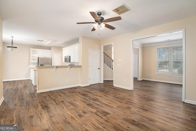 unfurnished living room featuring visible vents, dark wood-type flooring, ceiling fan, baseboards, and stairs