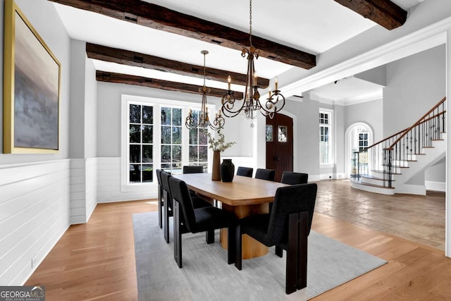 dining room featuring stairway, a wainscoted wall, light wood finished floors, an inviting chandelier, and arched walkways