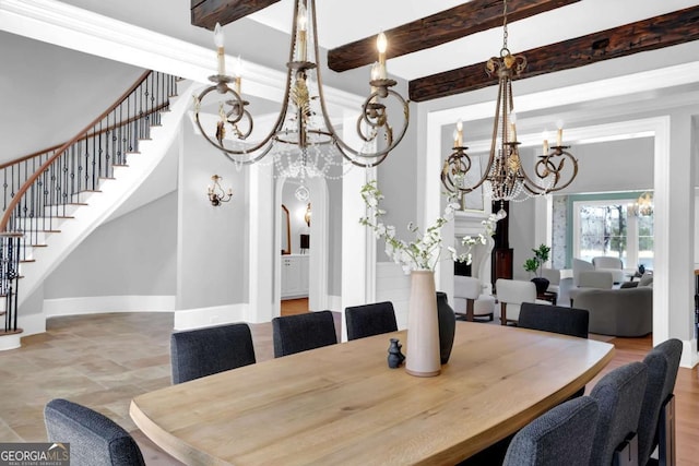 dining room with baseboards, beam ceiling, arched walkways, stairs, and a chandelier