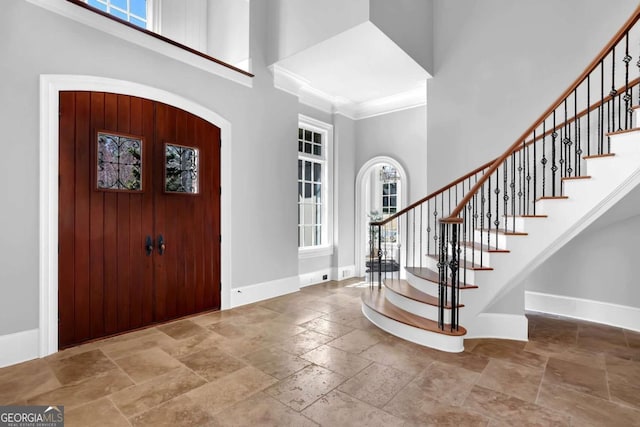 entrance foyer featuring stone tile flooring, baseboards, and a towering ceiling