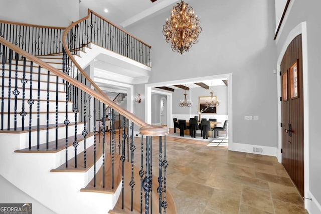 foyer with visible vents, baseboards, a high ceiling, and a chandelier