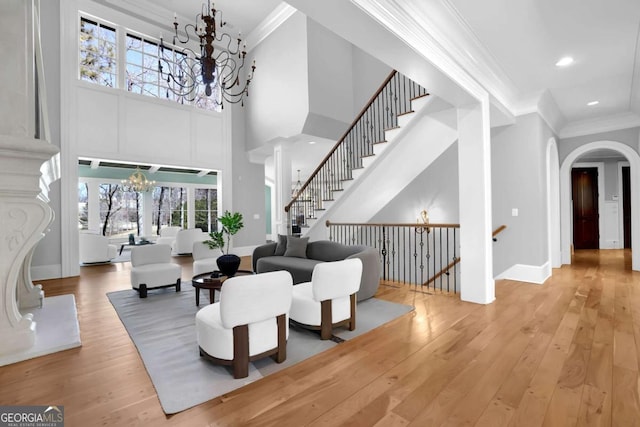 interior space with arched walkways, a notable chandelier, ornamental molding, and hardwood / wood-style flooring