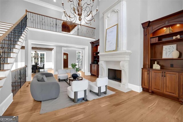 living room featuring light wood finished floors, a notable chandelier, a high ceiling, and a premium fireplace