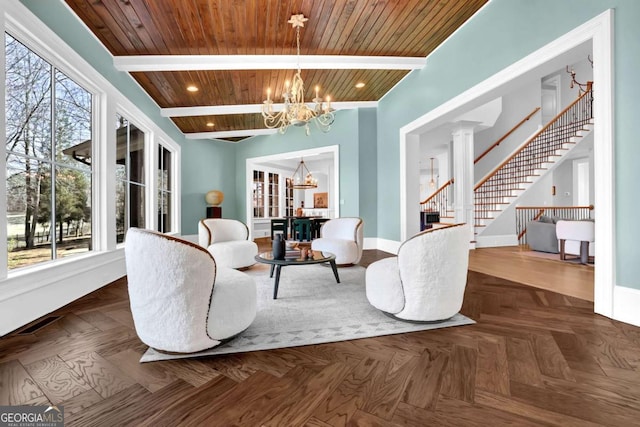 sitting room featuring stairs, an inviting chandelier, plenty of natural light, and beam ceiling